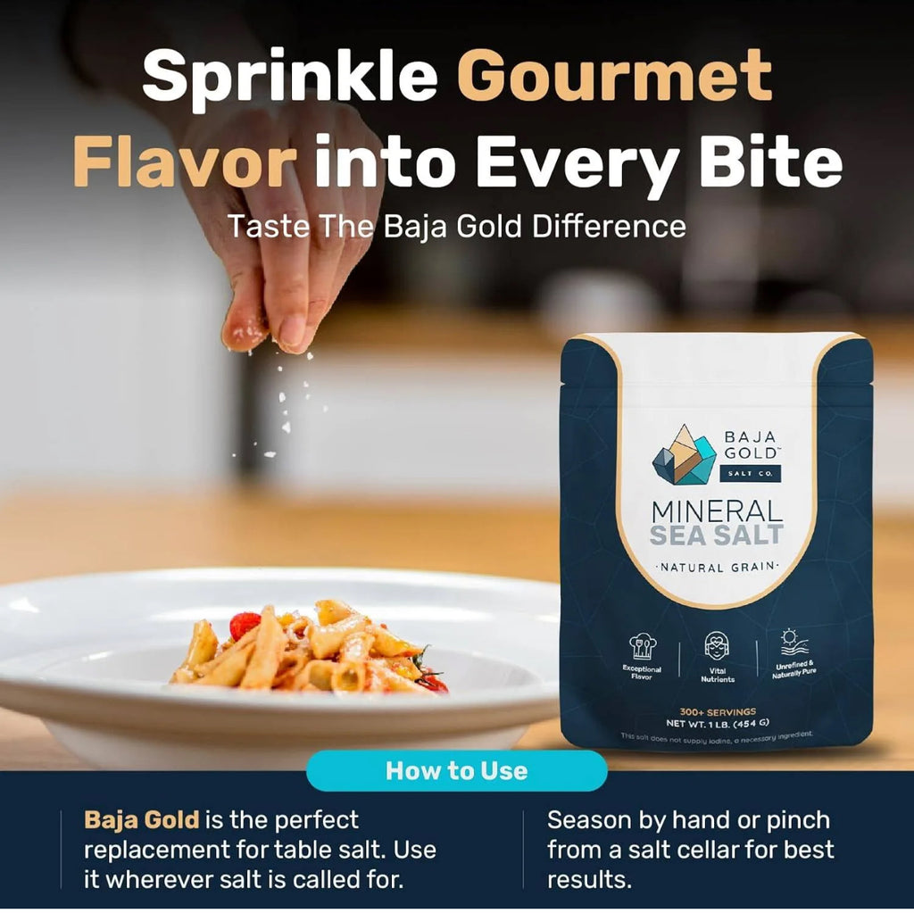 Baja Gold Mineral Sea Salt packaging with a hand sprinkling salt over pasta, on a blurred kitchen background.