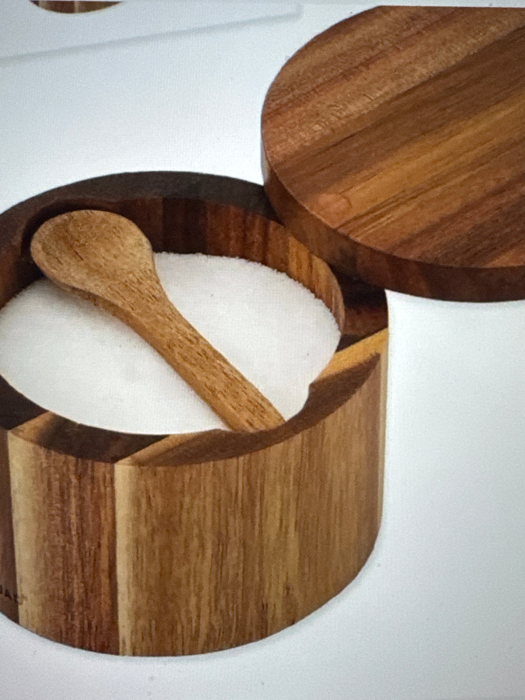Wooden salt cellar with a spoon and salt inside on a white background