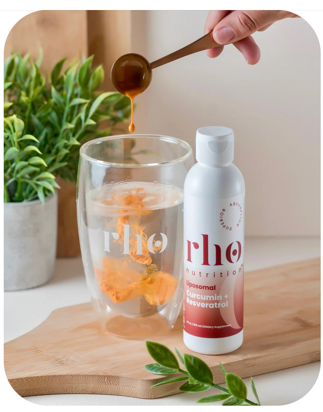 Person pouring a liquid into a glass with a bottle of 'rho' on a wooden board.