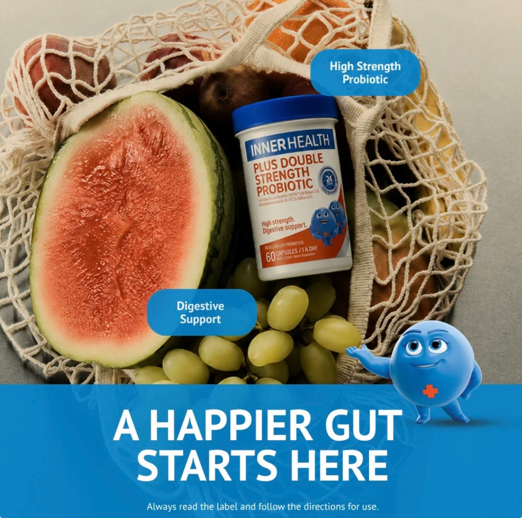 A container of INNERHEALTH Plus Double Strength Probiotic placed inside a beige mesh produce bag, surrounded by a watermelon half, green grapes, and oranges. Two blue callout bubbles read 'High Strength Probiotic' and 'Digestive Support,' with a blue cartoon character and the text 'A HAPPIER GUT STARTS HERE' on a blue banner at the bottom.