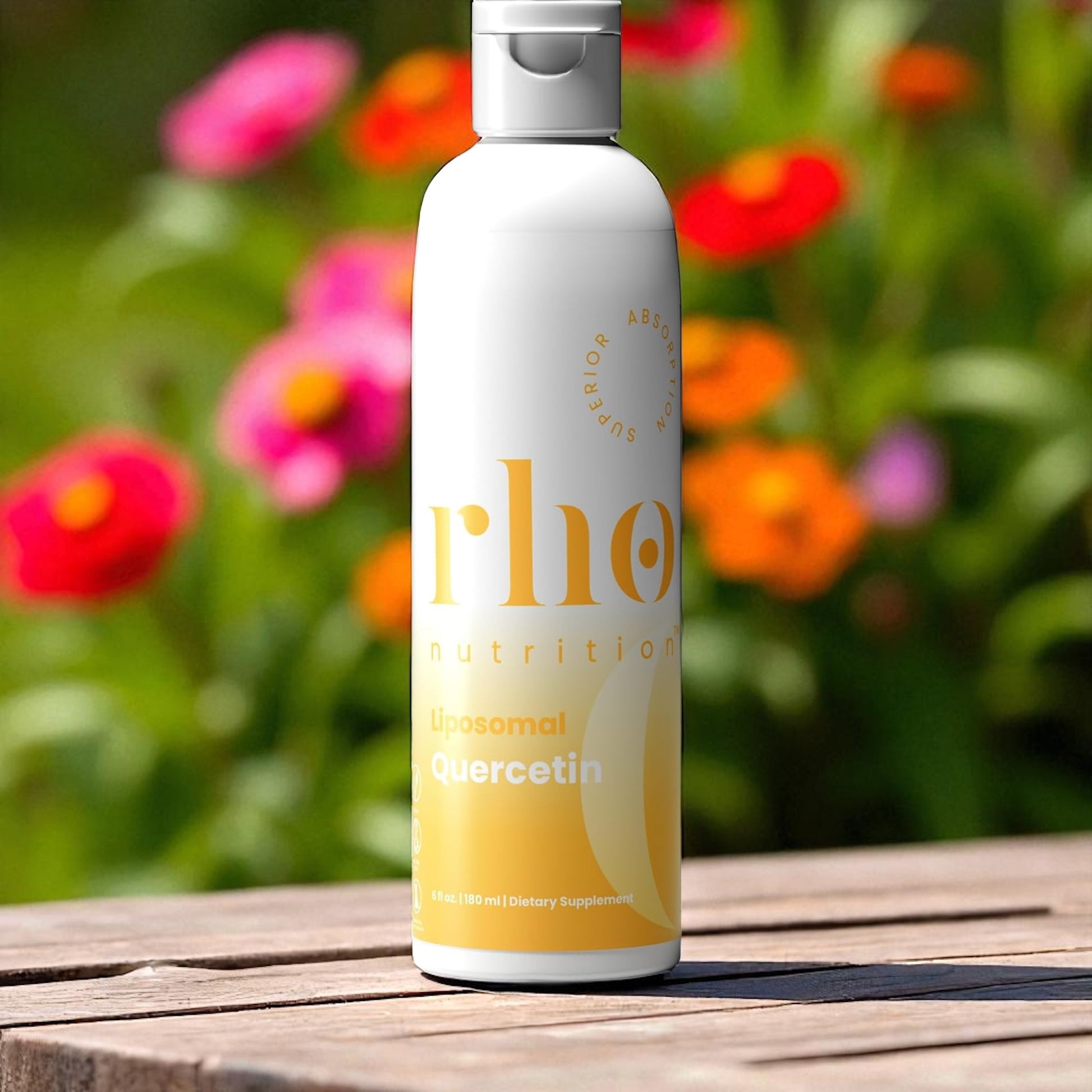 Bottle of rho nutrition supplement on a wooden surface with flowers in the background
